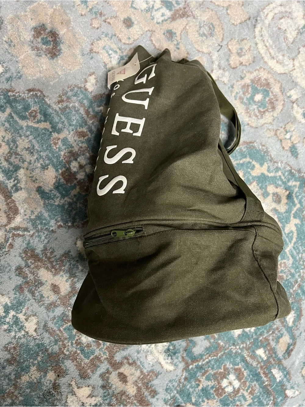 GUESS Olive Canvas Drawstring Sling Duffel Bag with zipper bottom.